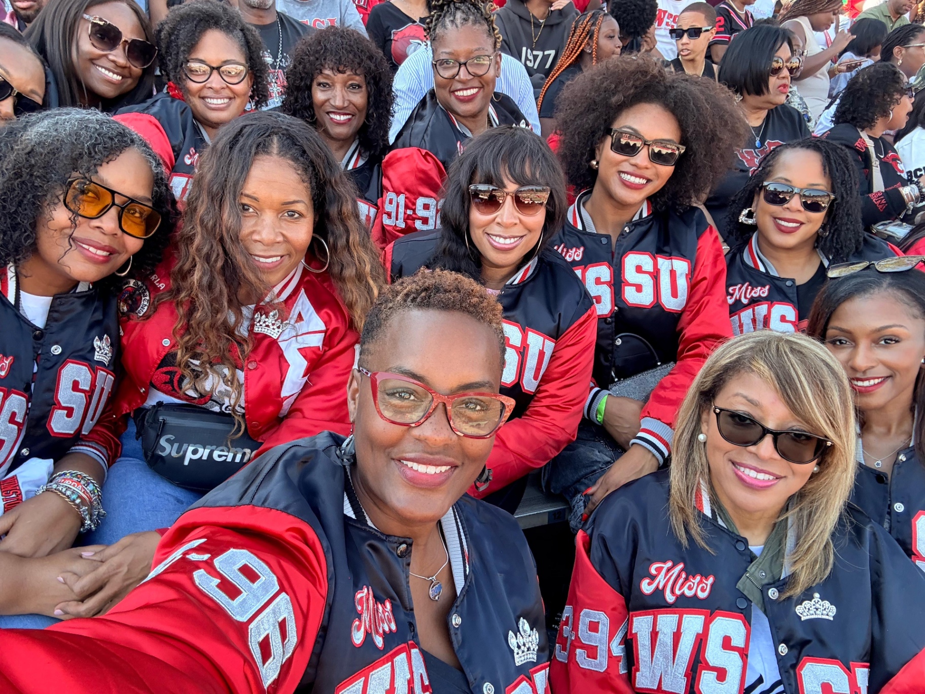 Alumnae queens in crimson and black WSSU jackets in the stands