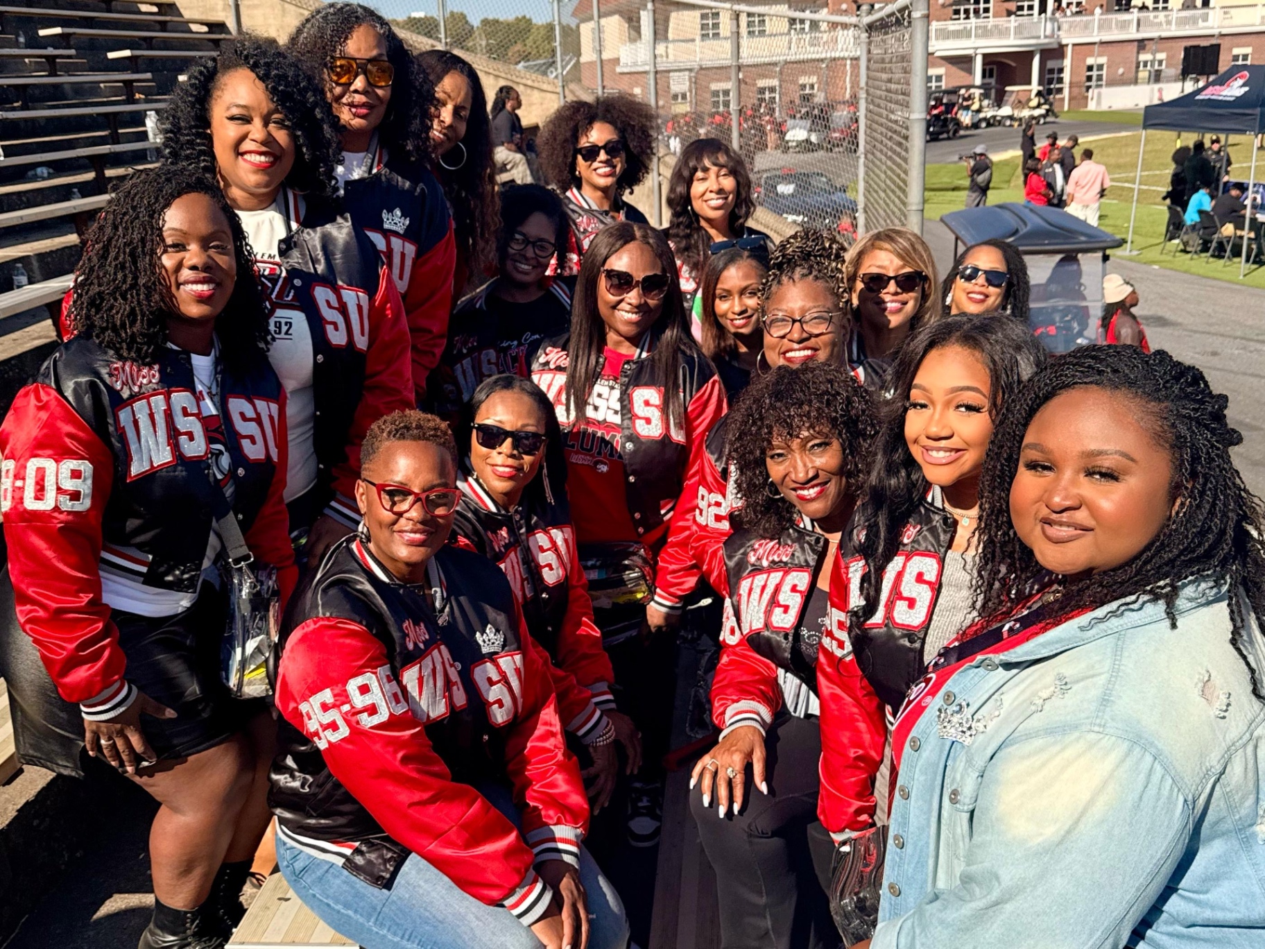 Large group portrait of alumnae queens in the stadium bleachers